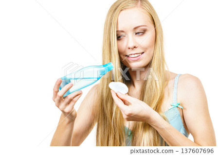 Woman cleaning her face skin with cotton pad Woman cleaning her face skin with cotton pad 137607696