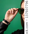 Close up of an anonymous hand adjusting stylish round sunglasses on a head 137607796
