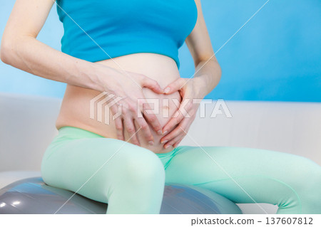 Pregnant woman making heart shape on belly with hands Pregnant woman making heart shape on belly with hands 137607812