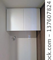 A white laundry cabinet with a faucet and outlet installed in the washing machine area of an apartment building 137607824