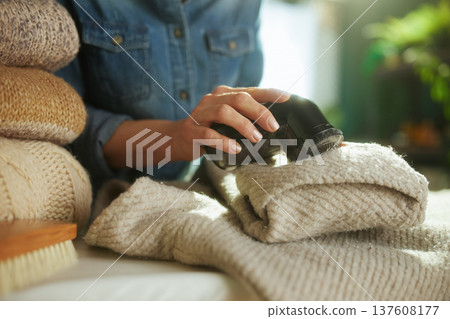 Refreshing a Stack of Knitted Sweaters with Lint Remover 137608177