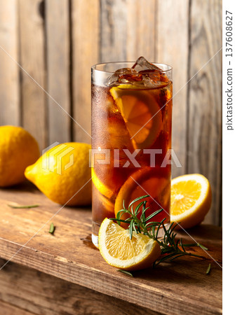 Iced tea or alcoholic cocktail with ice, rosemary and lemon slices on a old wooden table. 137608627