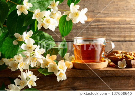 Glass cup of jasmine tea and green jasmine branches with flowers. 137608640