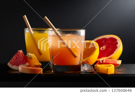 Grapefruit and orange juice with ice on a black background. Grapefruit and orange juice with ice on a black background. 137608646