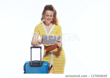 Woman Planning Vacation Itinerary on Tablet with Suitcase 137608695