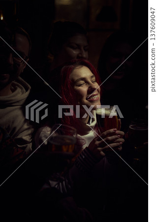 Woman enjoying beer while watching sports game with friends in pub during tense match moment 137609047