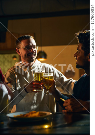 Friends encouraging each other with beer during emotional conversation in cozy pub atmosphere Friends encouraging each other with beer during emotional conversation in cozy pub atmosphere 137609054
