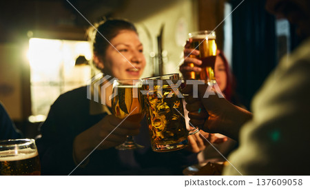 Close up beer toast between friends in pub during casual night out Close up beer toast between friends in pub during casual night out 137609058