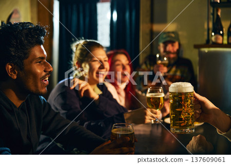 Friends laughing and drinking beer together in lively pub atmosphere during casual night out Friends laughing and drinking beer together in lively pub atmosphere during casual night out 137609061
