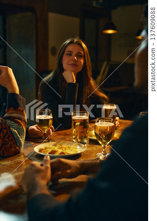 Woman enjoying beer conversation with friends in pub during relaxed social evening Woman enjoying beer conversation with friends in pub during relaxed social evening 137609088