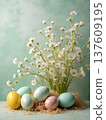 Colorful Easter eggs arranged with decorative straw and white daisies in a soft green background, creating a festive springtime display for the holiday celebration 137609195