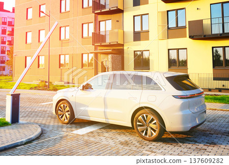Electric car drives out residential area. Auto stopped at barrier at building. EV car at car barrier 137609282