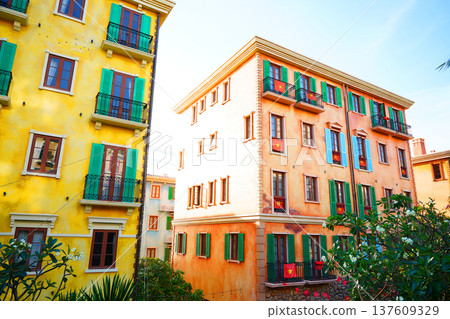 Sunlight shines on colorful buildings with plants in garden in european neighborhood. Sunlight shines on colorful buildings with plants in garden in european neighborhood. 137609329