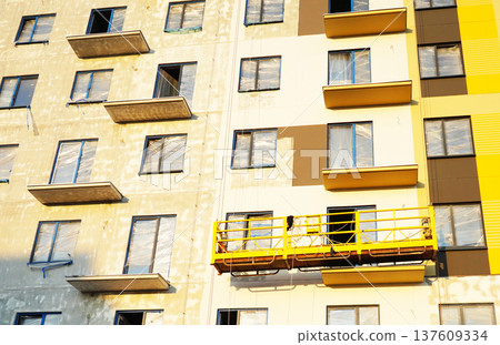 Suspended construction cradle on painting facade of building.  137609334