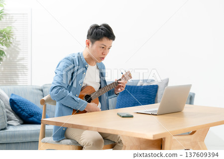 A man playing an ukulele 137609394