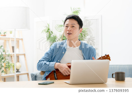 A man playing an ukulele A man playing an ukulele 137609395