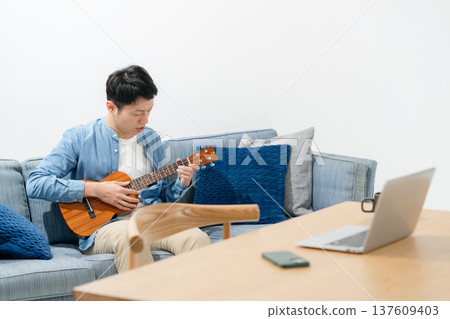 A man playing an ukulele A man playing an ukulele 137609403