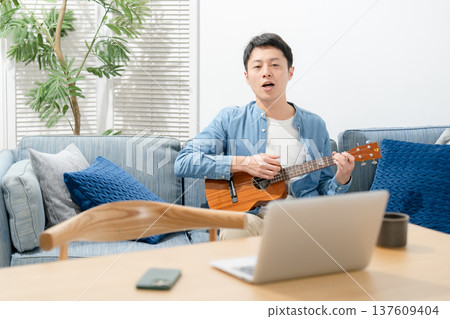 A man playing an ukulele 137609404