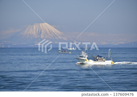 Photographing the scenery of Mt. Yotei and fishing boats passing through Funka Bay in Yakumo Town, Hokkaido in early spring 137609476