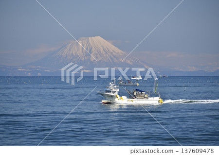 Photographing the scenery of Mt. Yotei and fishing boats passing through Funka Bay in Yakumo Town, Hokkaido in early spring 137609478