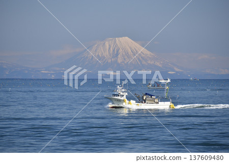 Photographing the scenery of Mt. Yotei and fishing boats passing through Funka Bay in Yakumo Town, Hokkaido in early spring Photographing the scenery of Mt. Yotei and fishing boats passing through Funka Bay in Yakumo Town, Hokkaido in early spring 137609480