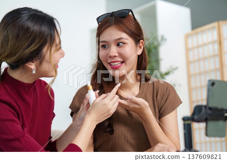 Beauty Sharing. Friends enjoying skincare tips and applying products together. 137609821