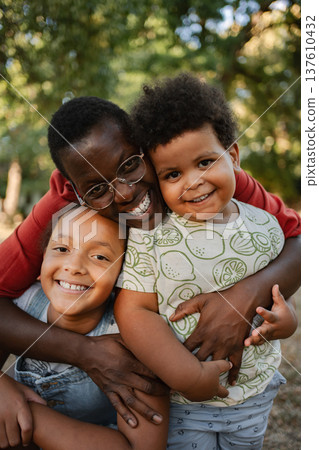 Mother Embracing her Two Children in a Park 137610432