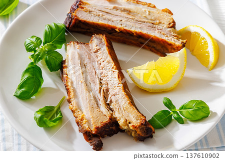 Roasted pork belly ribs with pesto and lemon 137610902