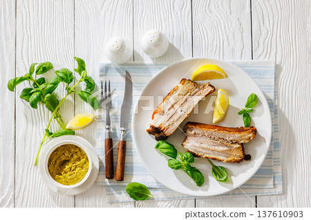 Roasted pork belly ribs with pesto and lemon 137610903