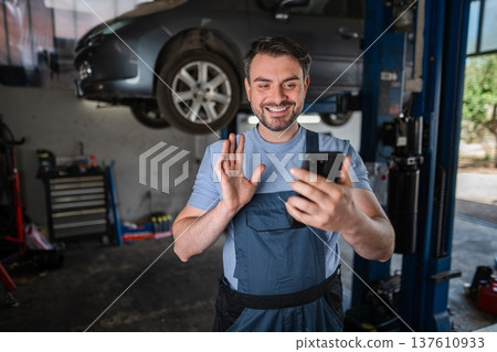 Car mechanic having a video call with a customer in a workshop 137610933