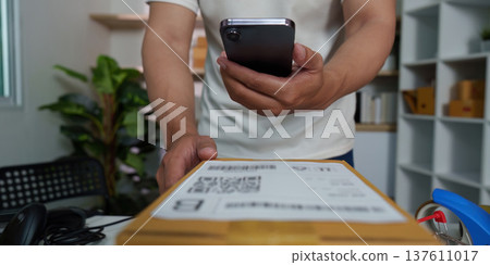 E-commerce. Man using smartphone to track package delivery at home office. E-commerce. Man using smartphone to track package delivery at home office. 137611017