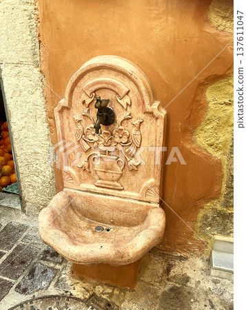 Antique marble water fountain on a stone wall in the historic center of Creta, Chania, Greece at 10 August 2023 137611047