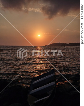 A fishing boat wreck rests on rocks at Kusadasi cliffs during golden hour in Turkey, Close-up shot of a beached shipwreck along the coast of Kusadasi, Augen, Turkey. A fishing boat wreck rests on rocks at Kusadasi cliffs during golden hour in Turkey, Close-up shot of a beached shipwreck along the coast of Kusadasi, Augen, Turkey. 137611065