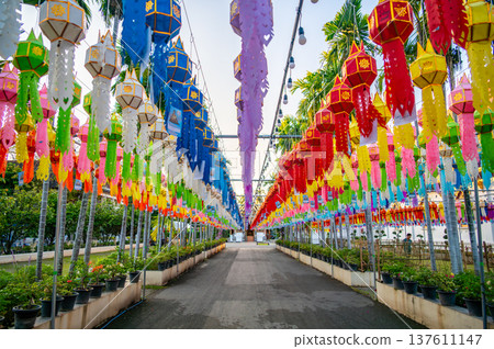 Colorful Buddhist prayer flags hanging from tree near temple in Thailand. Traditional decorations symbolizing blessings, peace and spiritual harmony fluttering gently in warm tropical air. Colorful Buddhist prayer flags hanging from tree near temple in Thailand. Traditional decorations symbolizing blessings, peace and spiritual harmony fluttering gently in warm tropical air. 137611147