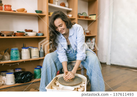 Young woman shaping clay on pottery wheel in ceramic workshop, handmade pottery process and creative craft activity in studio Young woman shaping clay on pottery wheel in ceramic workshop, handmade pottery process and creative craft activity in studio 137611493
