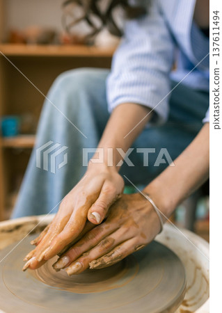 Close up of female hands shaping clay on pottery wheel in ceramic studio, handmade pottery process and traditional craft Close up of female hands shaping clay on pottery wheel in ceramic studio, handmade pottery process and traditional craft 137611494