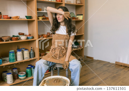 Young woman shaping clay on pottery wheel in ceramic workshop, handmade pottery process and creative craft activity in studio Young woman shaping clay on pottery wheel in ceramic workshop, handmade pottery process and creative craft activity in studio 137611501