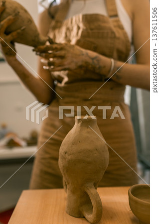 Young female ceramic artist holding handmade clay vase in pottery studio, creative craft process and handmade ceramics production Young female ceramic artist holding handmade clay vase in pottery studio, creative craft process and handmade ceramics production 137611506