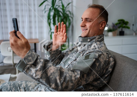 Smiling soldier making a video call from home Smiling soldier making a video call from home 137611614