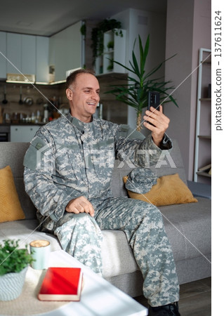 Smiling Soldier Video Calling Family While Relaxing on Sofa at Home Smiling Soldier Video Calling Family While Relaxing on Sofa at Home 137611624