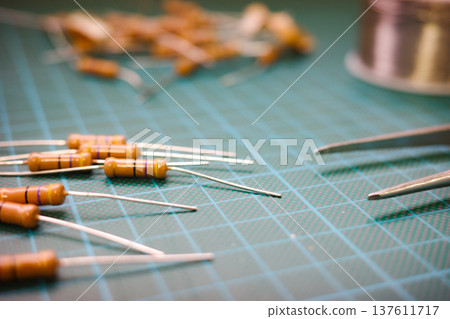 Electronic resistors and tweezers on cutting mat electronics workspace 137611717