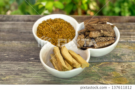 Assorted dried Thai medicinal herbs and wood chips on a white plate, placed on a rustic wooden table in a garden. Ideal for traditional medicine and natural healing themes Assorted dried Thai medicinal herbs and wood chips on a white plate, placed on a rustic wooden table in a garden. Ideal for traditional medicine and natural healing themes 137611812