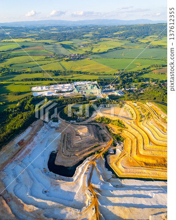 The sandstone quarry in Strelec shows layers of earth being extracted. The activity occurs in the Bohemian Paradise region. Surrounding fields stretch across the landscape. 137612355