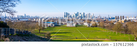 Visitors enjoy a sunny day in Greenwich Park, surrounded by greenery. The historic buildings contrast with the modern London skyline in the background, creating a beautiful scene. Visitors enjoy a sunny day in Greenwich Park, surrounded by greenery. The historic buildings contrast with the modern London skyline in the background, creating a beautiful scene. 137612366