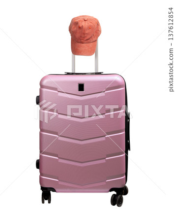 Wheeled suitcase, airport bag with pink baseball cap placed on top. Modern hard polycarbonate carry Wheeled suitcase, airport bag with pink baseball cap placed on top. Modern hard polycarbonate carry 137612854