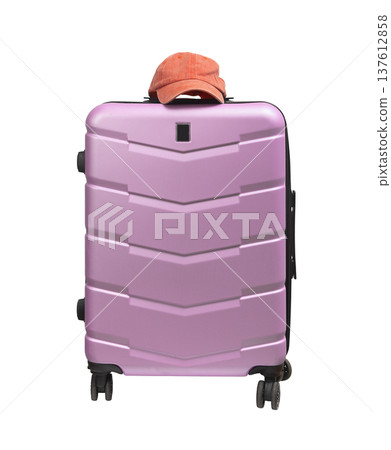 Front view, closed wheeled suitcase with pink baseball cap on top. Polycarbonate hardcase trolley Front view, closed wheeled suitcase with pink baseball cap on top. Polycarbonate hardcase trolley 137612858