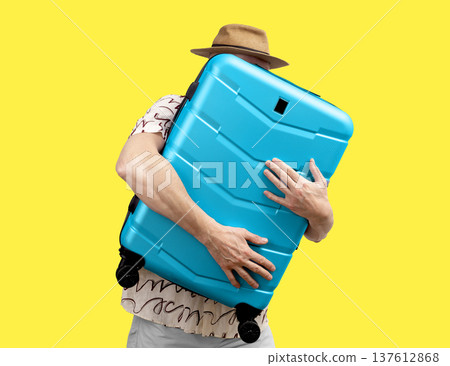 Man embracing suitcase. tourist in summer hat hugs large blue hardshell bag. Funky travel moment 137612868