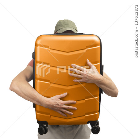 Man holding suitcase. Male traveler with funky hardshell carry-on, wearing cap and standing with 137612872