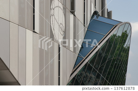 The stadium contemporary facade stands as a masterclass in modern industrial design, its taut geometric precision defined by a bold juxtaposition of materials : sleek, vertical metallic panels clad th 137612878