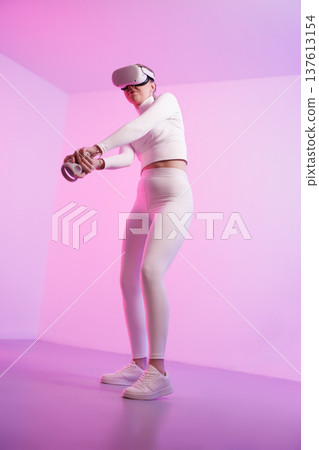Woman in VR glasses practicing golf against pink background 137613154